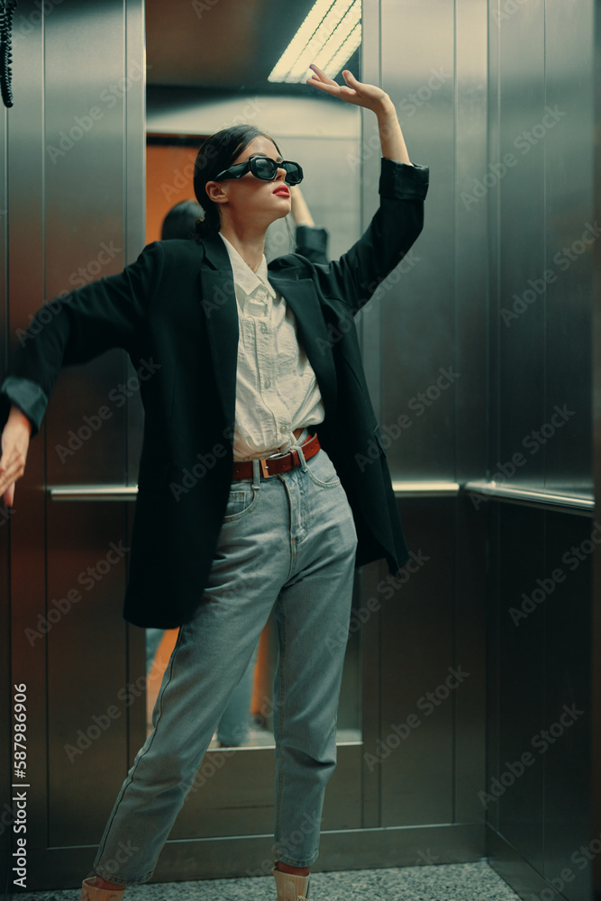Stylish woman in black jacket and sunglasses posing in elevator, fashion model Stylish woman in black jacket and sunglasses posing in elevator, fashion model
