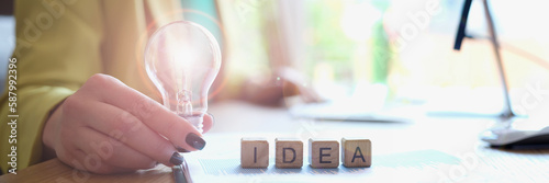 Businesswoman holds light bulb and on cubes word ideas closeup