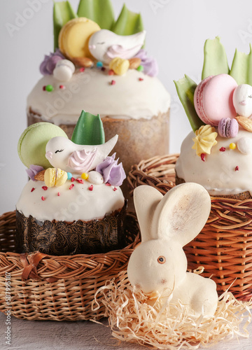 Easter cake with raisins and white fondant with birds and macaroons. on a light background with rabbits and flowers