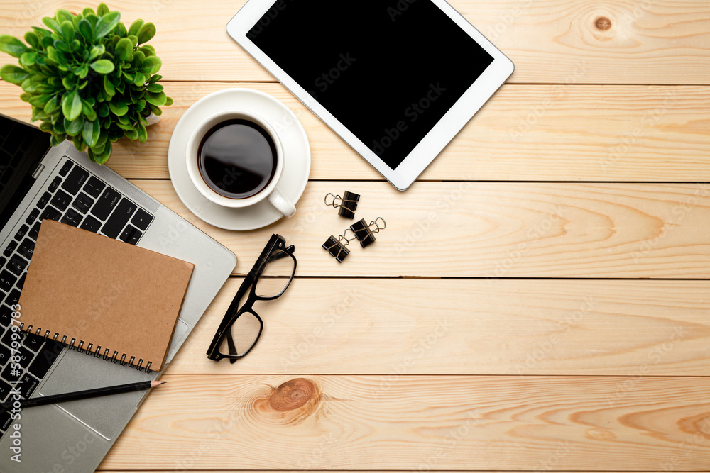 Top view office table desk. Workspace with blank, office supplies,Laptop, pencil, green leaf, and coffee cup on wood background. Top view office table desk. Workspace with blank, office supplies,Laptop, pencil, green leaf, and coffee cup on wood background.