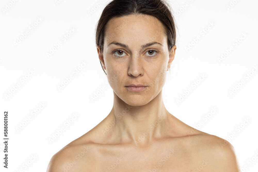 a young serious shirtless woman without makeup with long tied hair on a white background a young serious shirtless woman without makeup with long tied hair on a white background