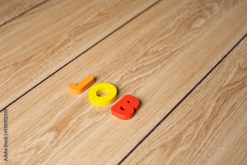 Closeup shot of colorful letter block "JOB" on wooden background. 
