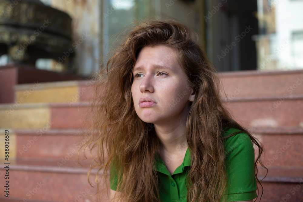 Obraz premium young beautiful woman is sitting on steps near hotel or new house, home and upset