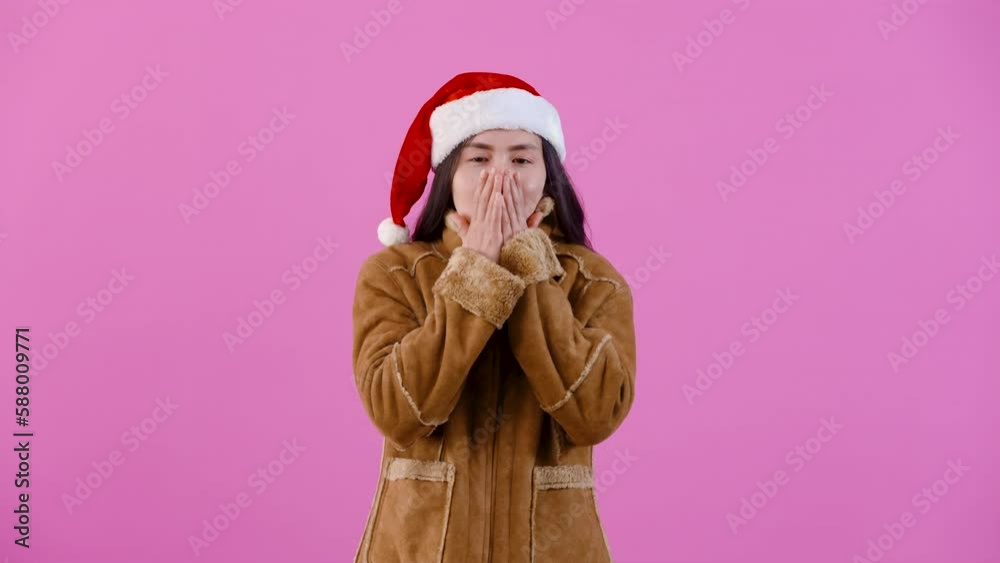 4K, portrait, Long-haired Asian girl in brown sweater wearing Christmas hat, put your hands on your chest blow air through your mouth, showing that are cold, Isolated indoor studio on pink background. 4K, portrait, Long-haired Asian girl in brown sweater wearing Christmas hat, put your hands on your chest blow air through your mouth, showing that are cold, Isolated indoor studio on pink background.