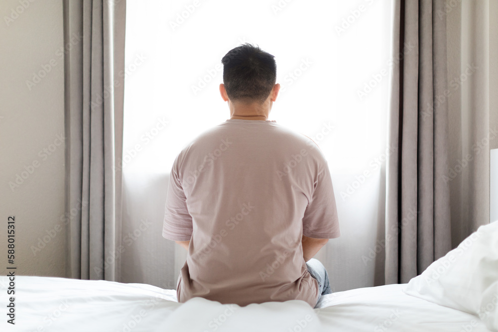 Unhappy man sitting alone on bed alone at home Unhappy man sitting alone on bed alone at home