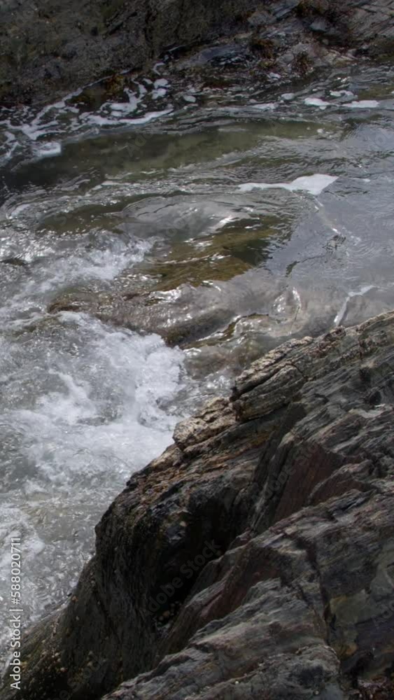 Coastal waves crash and produce a white bubbly foam. Vertical video. Coastal waves crash and produce a white bubbly foam. Vertical video.