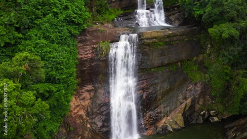 Jungle Waterfall in a tropical forest surrounded by green vegetation. Thaliya Wetuna Ella Falls in mountain jungle. Sri Lanka. photo