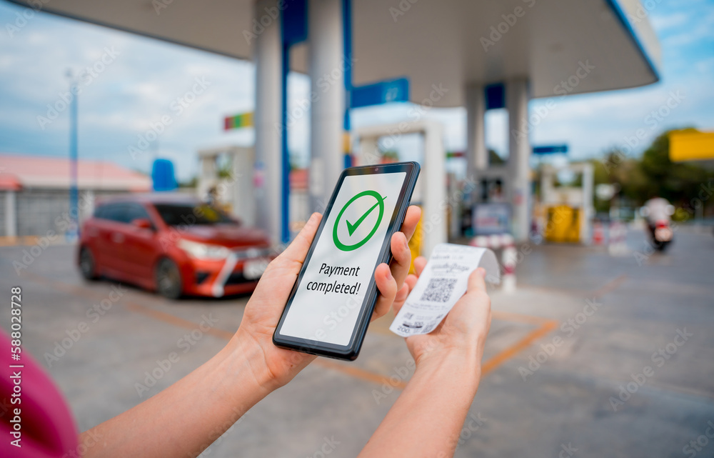 Woman using contactless payment by mobile phone with QR code at car filling station Woman using contactless payment by mobile phone with QR code at car filling station