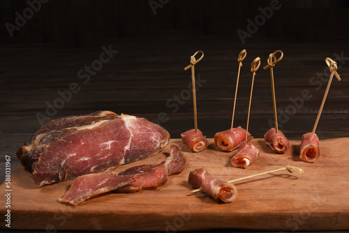 Dried Processed Beef Jerky. Cooking the meat spicy rolls with snack sticks on wooden board against dark background.