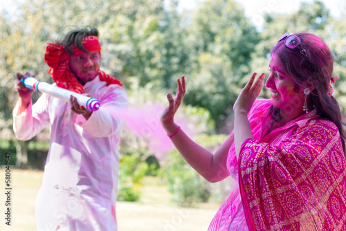 Indian young couple celebrating Holi with pichkari