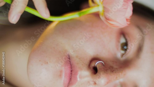 An attractive woman. Close-up portrait with flowers. Ranunculus and female face. Healthcare with nature. 