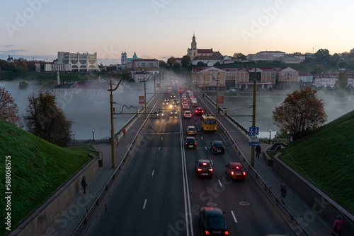 Belarus  Grodno July 15  2022  The movement of cars and public transport on the bridge over the river. Thick morning fog over the bridge in the city. fog over a crowded road