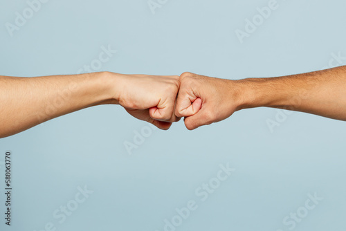Close up shot of couple two male friends men together hold hands folded fist bump gesture isolated on pastel plain light blue cyan color background studio portrait. Friendship business greet concept.