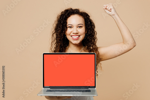 Happy young IT woman bride wear wedding dress posing hold use work blank screen workspace laptop pc computer do winner gesture isolated on plain beige background. Ceremony celebration party concept. © ViDi Studio