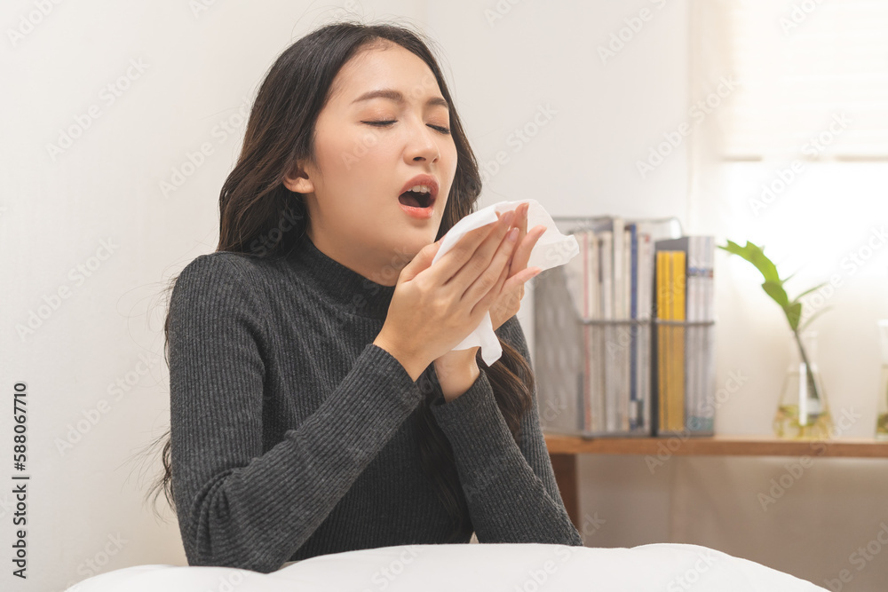 Seasonal sick, illness asian young woman, girl expression weak, tired face under blanket have fever, flu and use tissues paper sneezing nose, runny sitting on bed at home. Health care on virus person. Seasonal sick, illness asian young woman, girl expression weak, tired face under blanket have fever, flu and use tissues paper sneezing nose, runny sitting on bed at home. Health care on virus person.