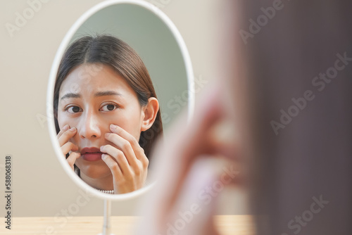 Dermatology, puberty asian young woman, girl looking into mirror, allergy presenting an allergic reaction from cosmetic, red spot or  rash on face. Beauty care from skin problem by medical treatment.
