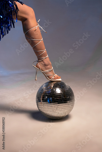 Female leg in beautiful white sandals on a disco ball