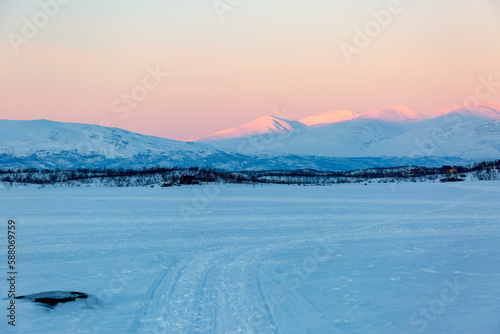 Abisko in Lapponia in Svezia. Tramonto al lago di Tornetrask ghiacciato. Sole, neve, ghiaccio, al circolo polare artico, un paesaggio del nord Europa photo