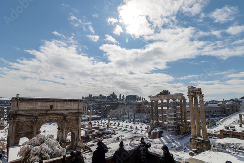  Imperial Forums, Roman forum on a snowy day in Rome, Italy. Roman snow-covered colosseum archaeological park. Titus Arch under snow