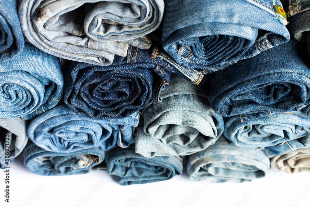 Stack of various shades blue jeans. Jeans stacked isolated on white background. Blue denim jeans texture banner with copy space for text design background. Canvas denim fashion texture Stack of various shades blue jeans. Jeans stacked isolated on white background. Blue denim jeans texture banner with copy space for text design background. Canvas denim fashion texture