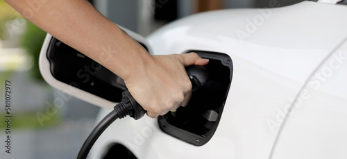 Progressive concept of hand insert an emission-free power connector to the battery of electric vehicle at home. Electric vehicle charging via cable from charging station to EV car battery