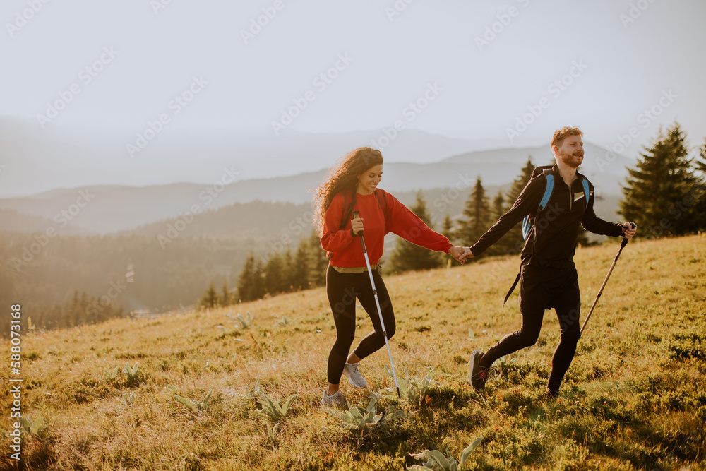 Young couple walking with backpack over green hills