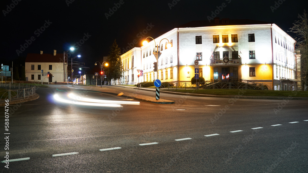 Fototapeta premium Night city light lines from cars. cars in highway with blur motion. Street view of the modern city at night. A lot of light from car headlights, advertising banners and night lights.