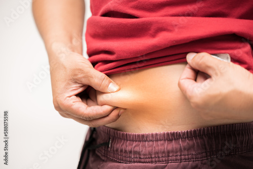 Wallpaper Mural Red shirt man using his hand to squeeze out excess fat isolated on a white background.Lose weight concept of abdominal fat surgery. Torontodigital.ca