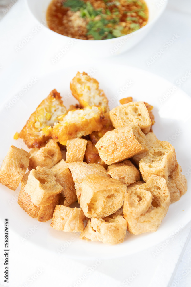 Deep fried tofu on white plate with peanut sweet and sour dipping sauce. Deep fried tofu on white plate with peanut sweet and sour dipping sauce.