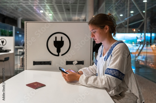 Girl charging her phone at the airport during the night.