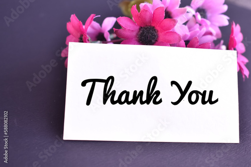A closeup picture of a Thank you card with Pink flowers