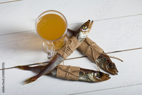 Putassu Cold smoked. The fish is wrapped with a strip of paper. Tied with linen twine. Glass with beer. Close-up. photo