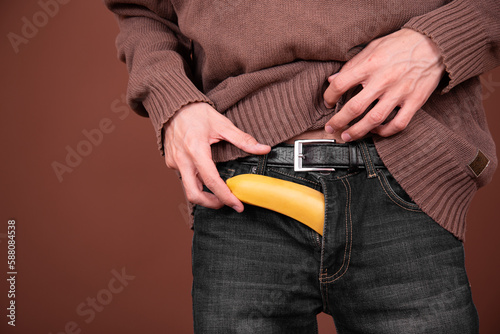 Young man with a banana on a brown background.