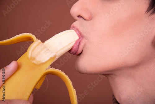 Young man with a banana on a brown background.