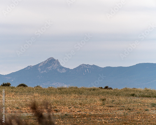 Landscape, dry grass with mountains on the background, on a cloudy day. © MiguelAngel