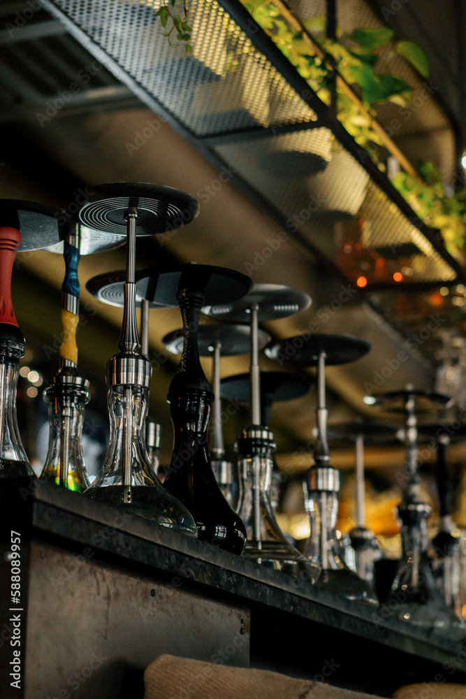 various hookahs with smoking equipment on shelves in lounge bar flasks pipes bowls recreation concept