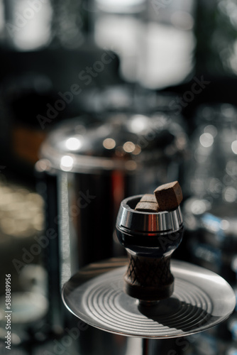 close-up of coal cubes lie in the bowl of a hookah with a metal rim of a lounge bar