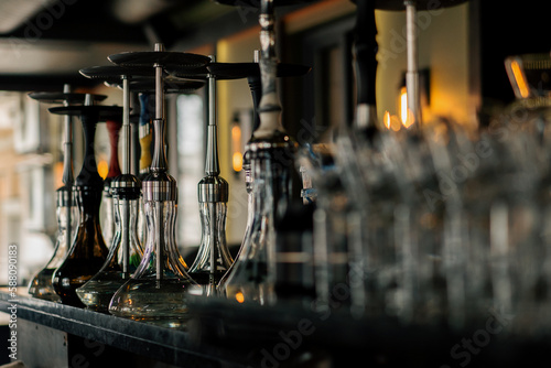 various hookahs with smoking equipment on shelves in lounge bar flasks pipes bowls recreation concept