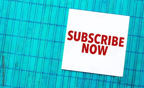subscribe now word on torn paper with blue wooden background