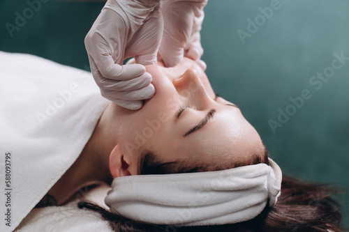 Cosmetologist makes a buccal massage of the patient's facial muscles in spa. Close up. photo