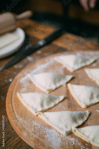 Men's hands make triangular pies with stuffing. Close-up. The cook cooks pies from the dough.