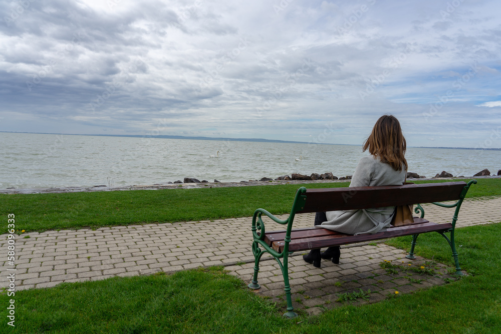 woman sitting on a bench next to lake Balaton in Hungary spring