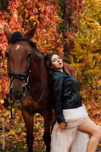 Bride in white dress near a horse in the autumn forest