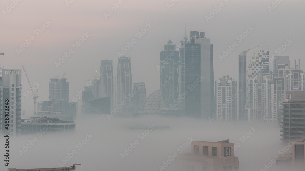 Fototapeta premium Dubai skyscrapers with morning fog in business bay district night to day timelapse.