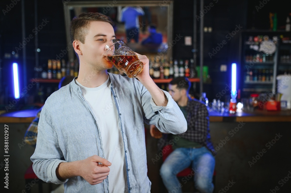 Tasting a good beer. Portrait of thoughtful men drinking beer at the bar Tasting a good beer. Portrait of thoughtful men drinking beer at the bar