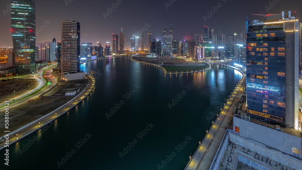 Cityscape of skyscrapers in Dubai Business Bay with water canal aerial all night timelapse