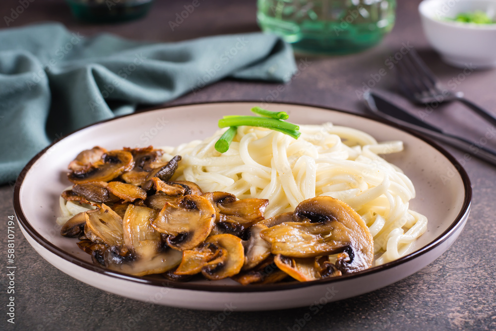 Udon noodles and fried mushrooms on a plate for homemade dinner Udon noodles and fried mushrooms on a plate for homemade dinner