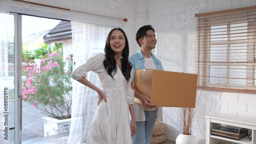 Asian couple carrying boxes into their new home on moving day.