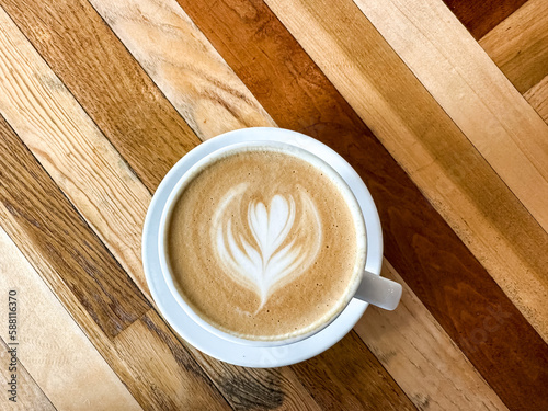 A cup of coffee latte on a wooden table. A mug of flat white coffee, latte, cappuccino on a wooden background. Coffee art. Heart flower swan shape latte art