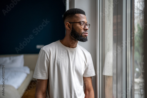 Tableau sur toile Sad Black man looking out of window thinking about life problems